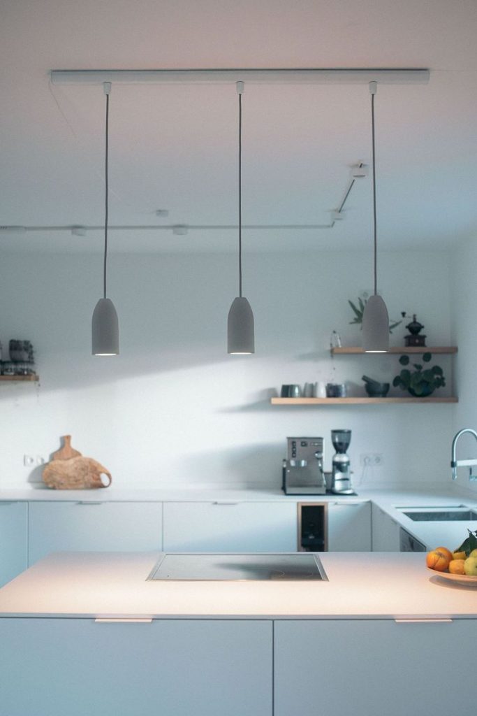 Helle Küche mit 3er Betonlampe über dem Kochfeld